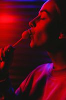 Woman lit in red licking a lollipop